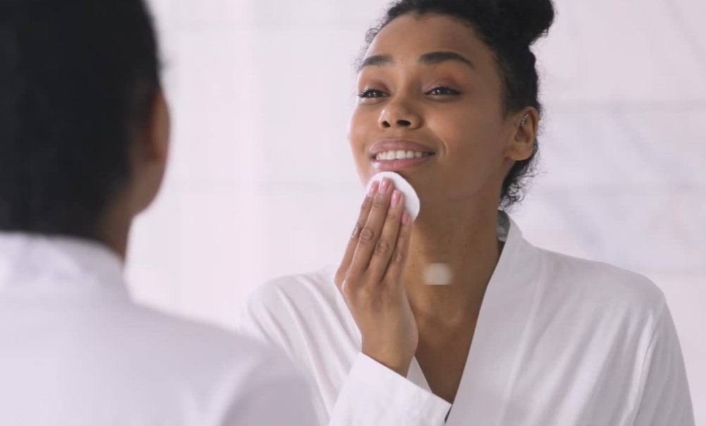 Woman cleansing her face with cotton pad